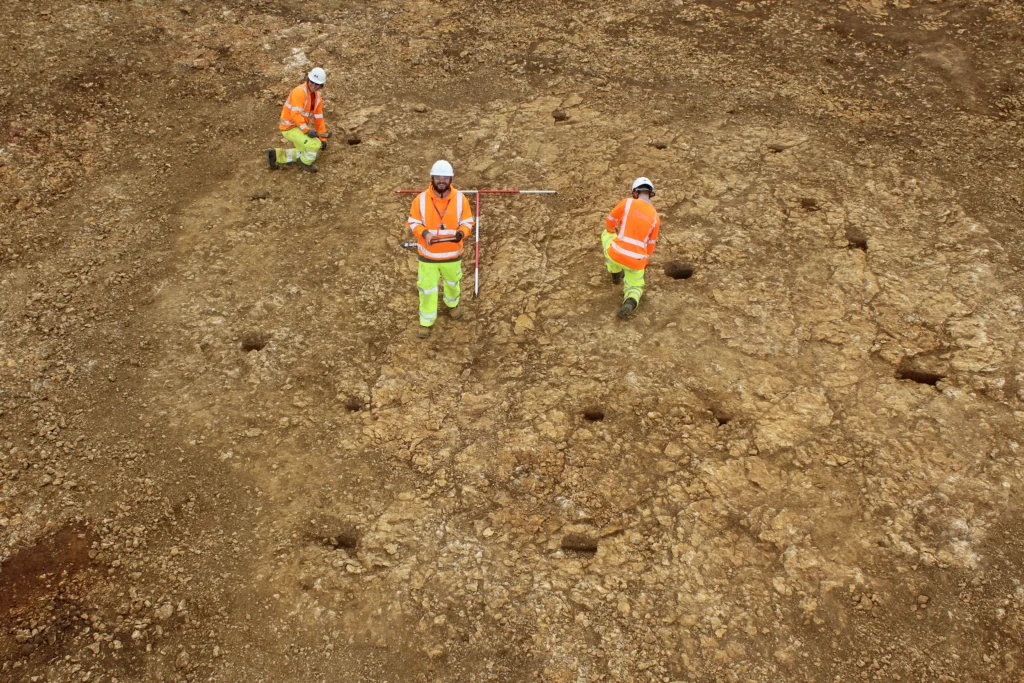 Drone photo of round house, can see the post holes and archaeologists setting up to take the record photos
