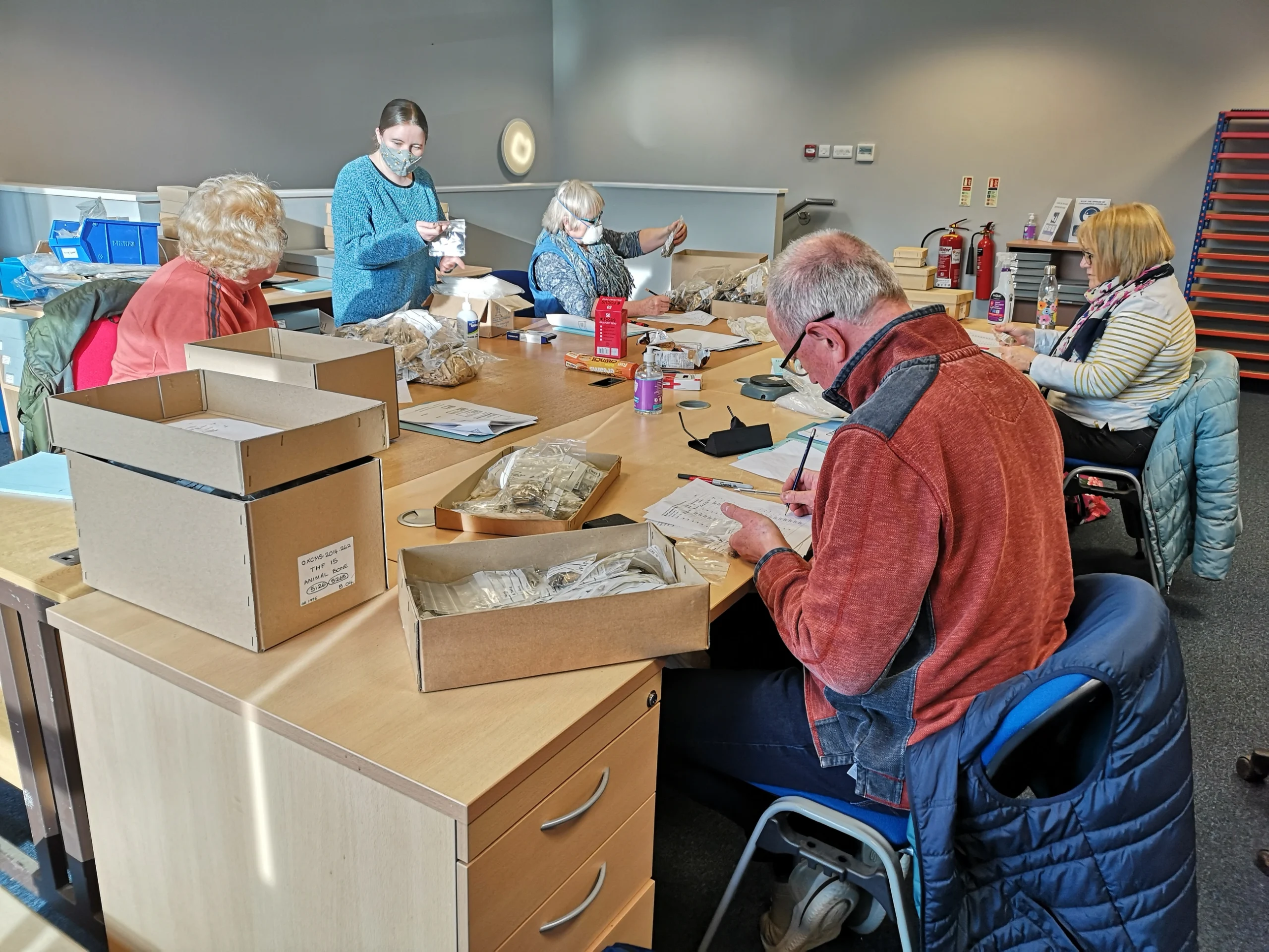 Volunteers set around tables marking, packaging and boxing artefacts.
