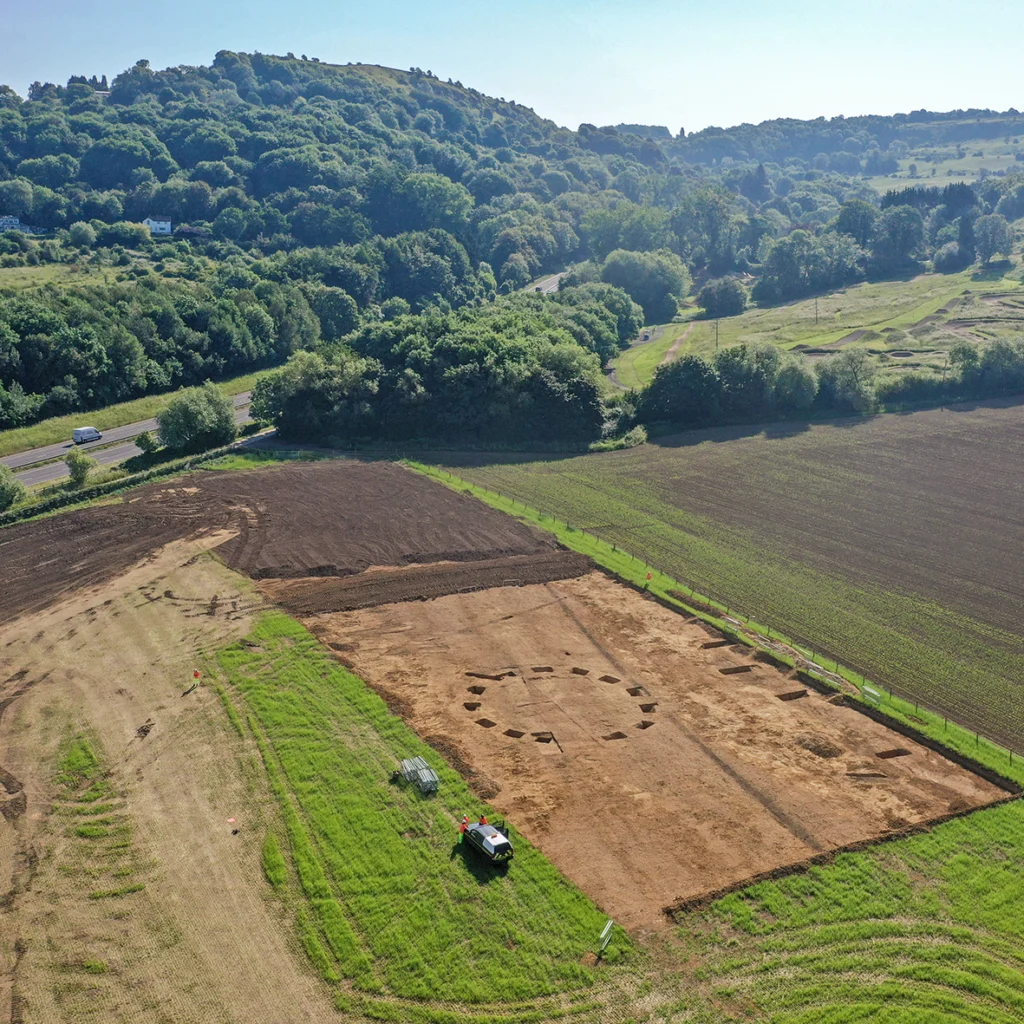 Aerial view of archaeological site, showing a circular feature in the foreground. 