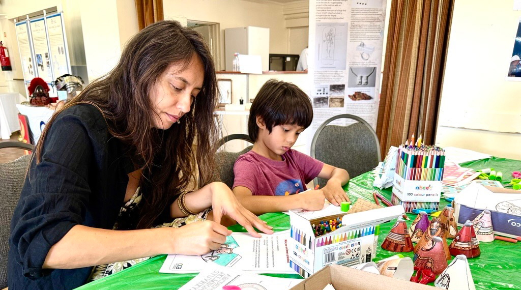 A mother and son sat at a table colouring in activity sheets