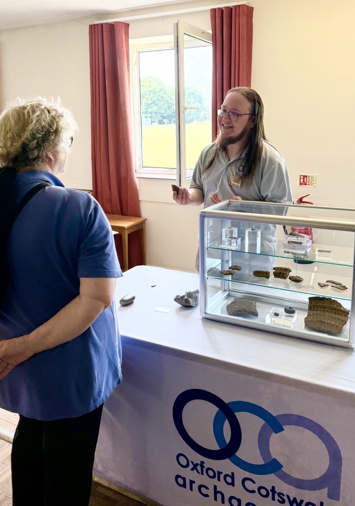 Photo of an OCA staff member showing a visitor replicas from next to a display case