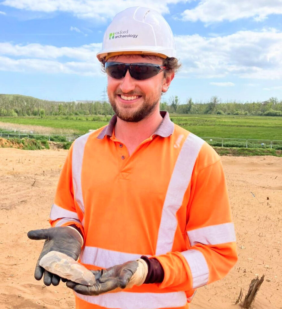 Image of an archaeologist holding and displaying a polished axe