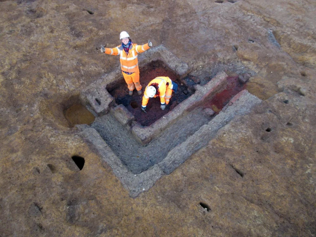 photo taken for above of the excavated corn dryer with two archaeologists one look at the camera with two thumbs up