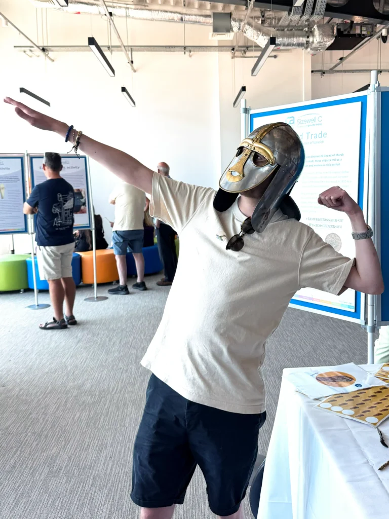 A person wearing a Sutton Hoo helmet replica posing like Usain Bolt
