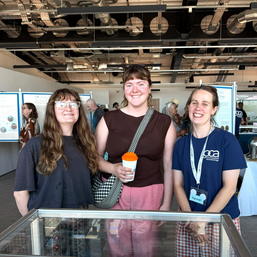 Three people smile from behind a glass display case