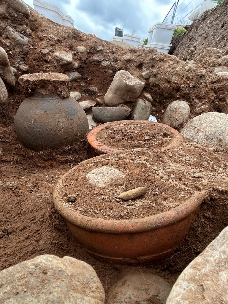 Image shows three Roman pottery vessels laying within a cremation.